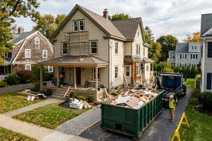 Roll-off dumpster filled with renovation waste and debris, set up beside a New England home during a home renovation project.